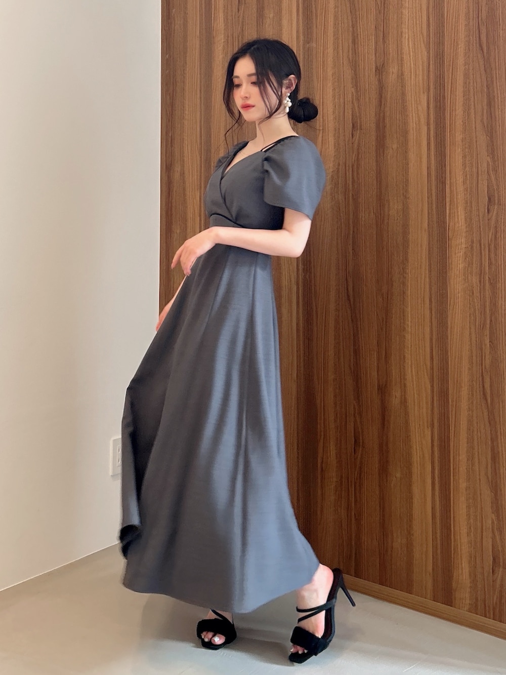 グレー系のワンピース、ゴールド系のピアス（両耳用）を着用したレディースの春コーディネートの2枚目の写真