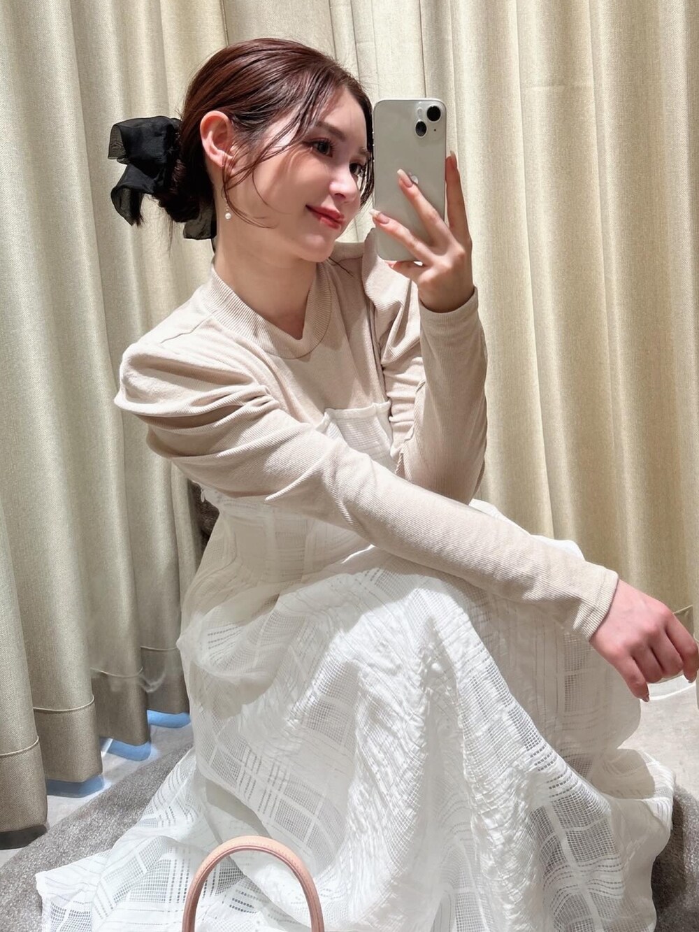 ブラック系のワンピース、ピンク系のハンドバッグ、ゴールド系のピアス（両耳用）を着用したレディースの冬コーディネートの2枚目の写真