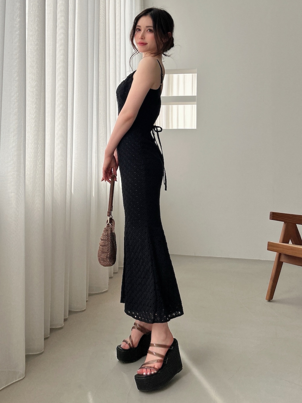 ブラック系のワンピース、ブラック系のサンダル、ブラウン系のハンドバッグを着用したレディースの春コーディネートの2枚目の写真