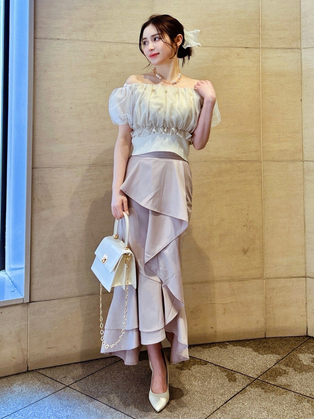 ピンク系のスカート、ホワイト系のシャツ/ブラウス、ホワイト系のハンドバッグを着用したレディースの春コーディネートの2枚目の写真