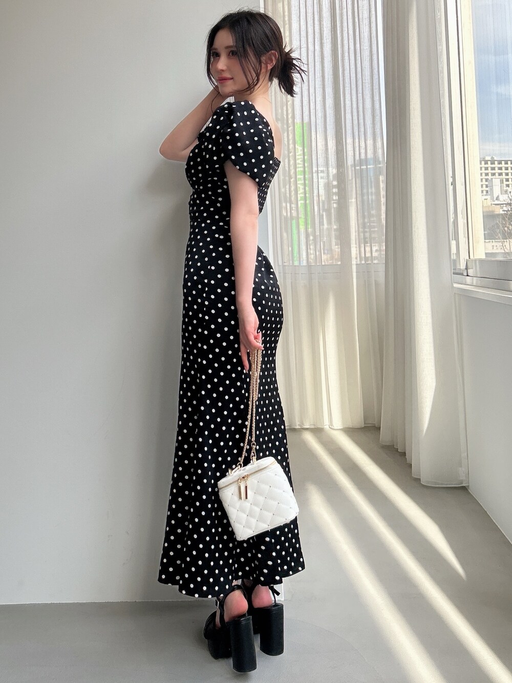 ブラック系のワンピース、ホワイト系のショルダーバッグ、ブラック系のサンダルを着用したレディースの春コーディネートの2枚目の写真