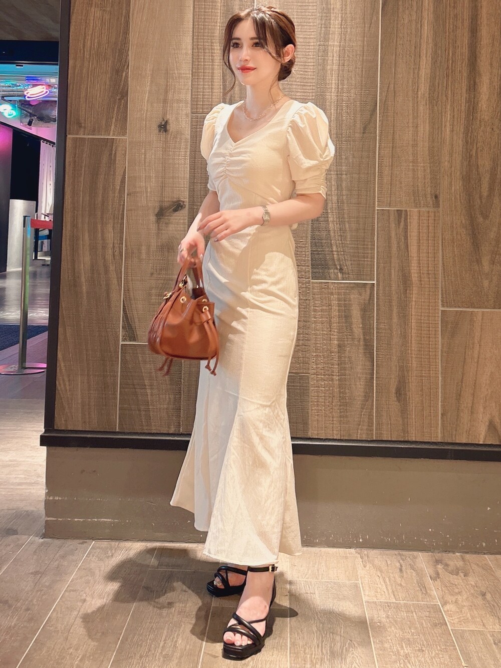 ホワイト系のワンピース、ブラウン系のハンドバッグ、ゴールド系のネックレスを着用したレディースの秋コーディネートの3枚目の写真