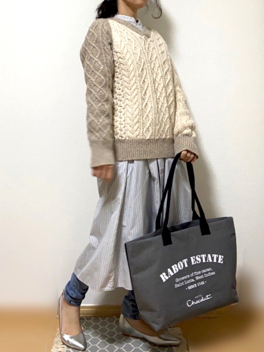 グレー系のトートバッグ、ブルー系のデニムパンツ、シルバー系のパンプスを着用したレディースの冬コーディネートの2枚目の写真