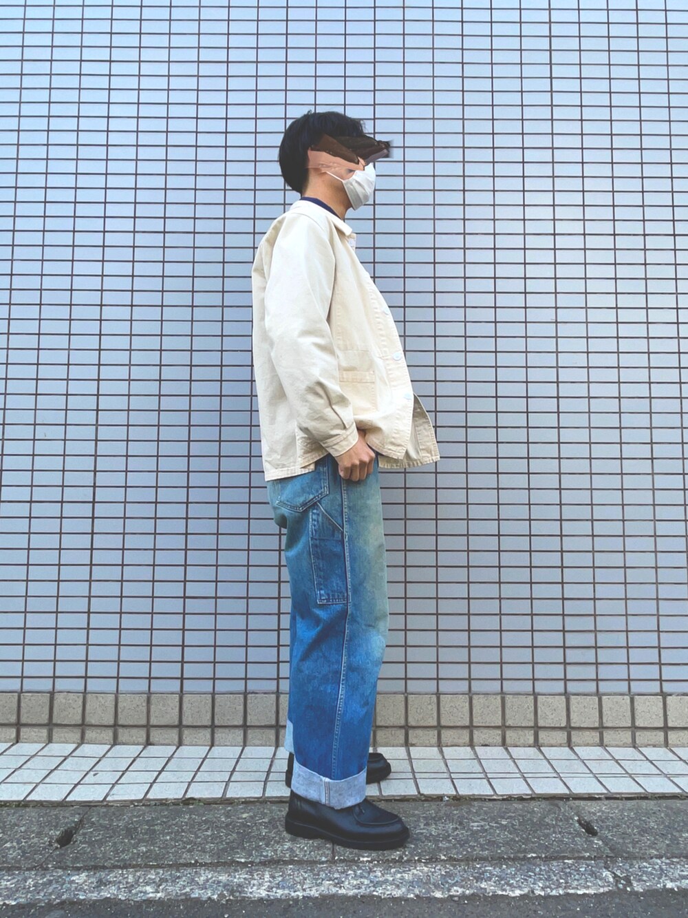 ホワイト系のカバーオール、ブラック系のドレスシューズ、ブルー系のデニムパンツを着用したメンズの冬コーディネートの2枚目の写真