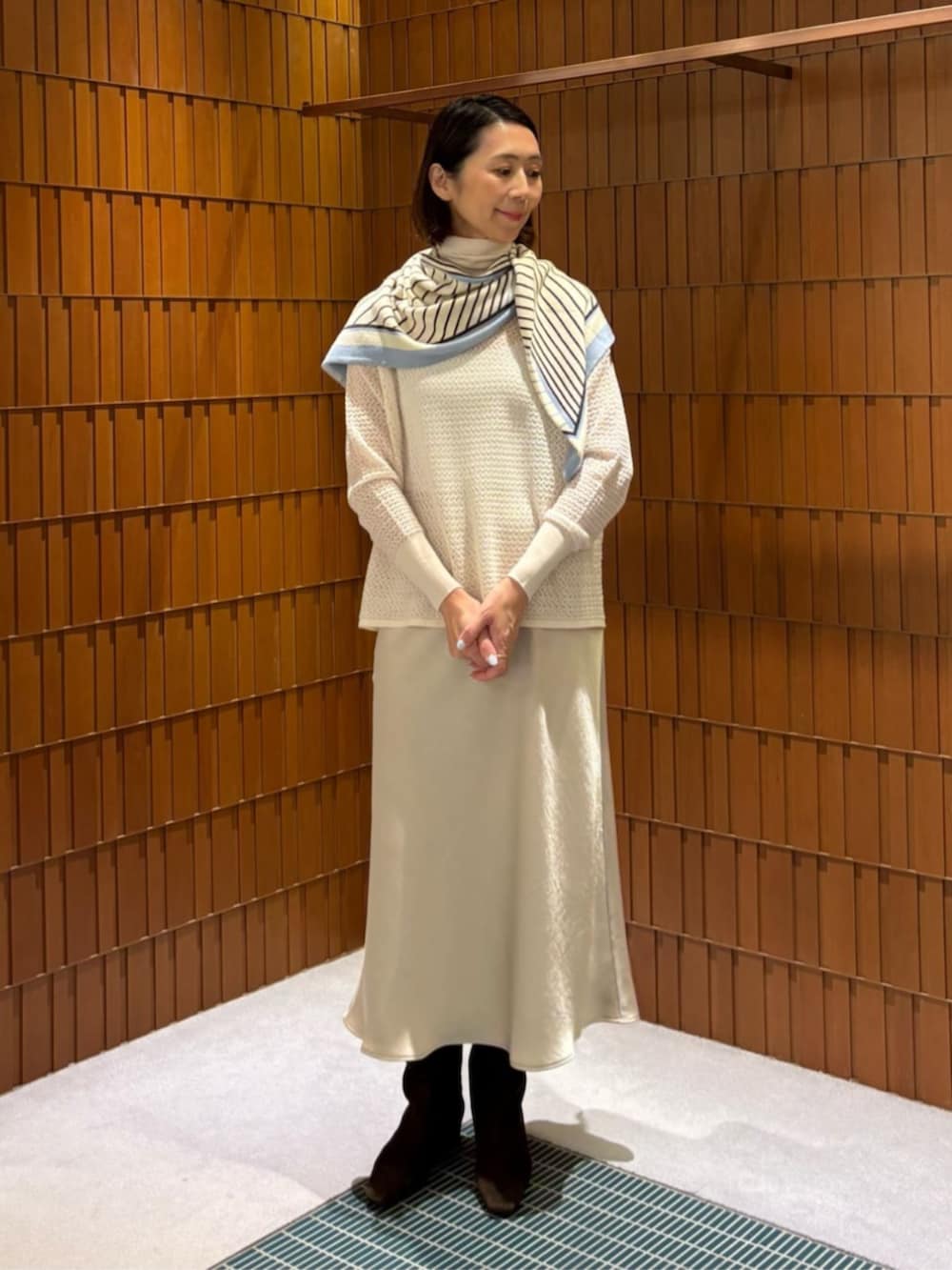 イエロー系のノーカラーコート、ホワイト系のニット/セーター、ベージュ系のスカートを着用したレディースの秋コーディネートの4枚目の写真