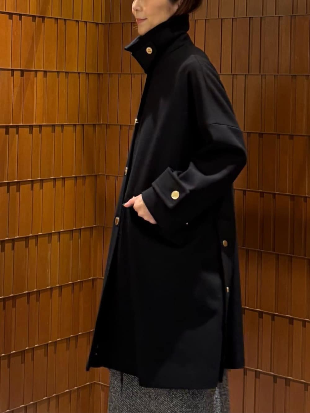 ブラック系のブーツ、ブラック系のステンカラーコート、ブラック系のニット/セーターを着用したレディースの秋コーディネートの3枚目の写真