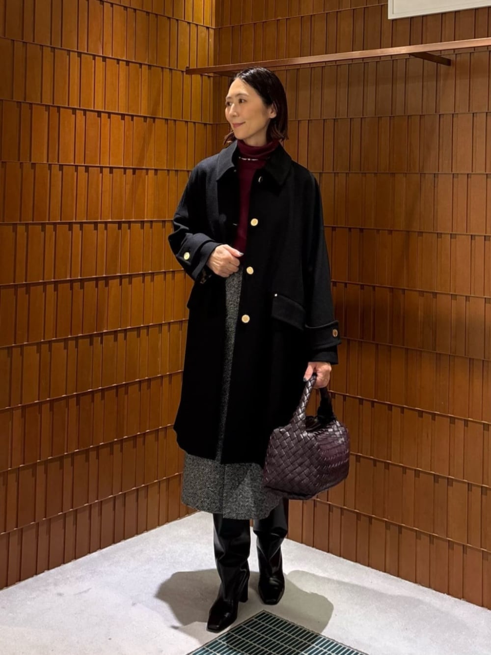 ブラック系のブーツ、ブラック系のステンカラーコート、ブラック系のニット/セーターを着用したレディースの秋コーディネートの5枚目の写真