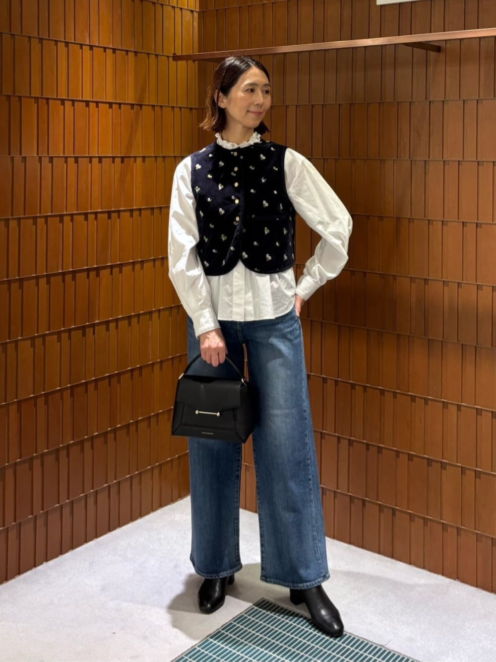 ブルー系のデニムパンツ、ホワイト系のシャツ/ブラウス、ブラック系のチェスターコートを着用したレディースの秋コーディネートの2枚目の写真