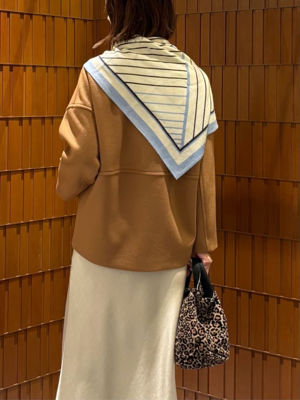 イエロー系のノーカラーコート、ホワイト系のニット/セーター、ベージュ系のスカートを着用したレディースの秋コーディネートの6枚目の写真