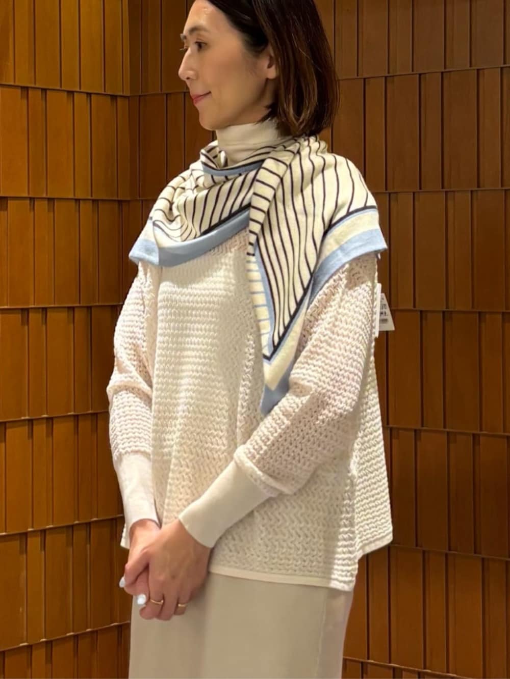 イエロー系のノーカラーコート、ホワイト系のニット/セーター、ベージュ系のスカートを着用したレディースの秋コーディネートの5枚目の写真