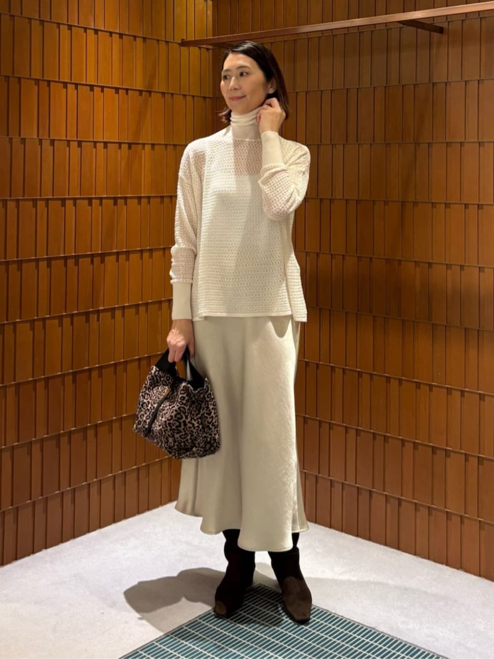 イエロー系のノーカラーコート、ホワイト系のニット/セーター、ベージュ系のスカートを着用したレディースの秋コーディネートの3枚目の写真