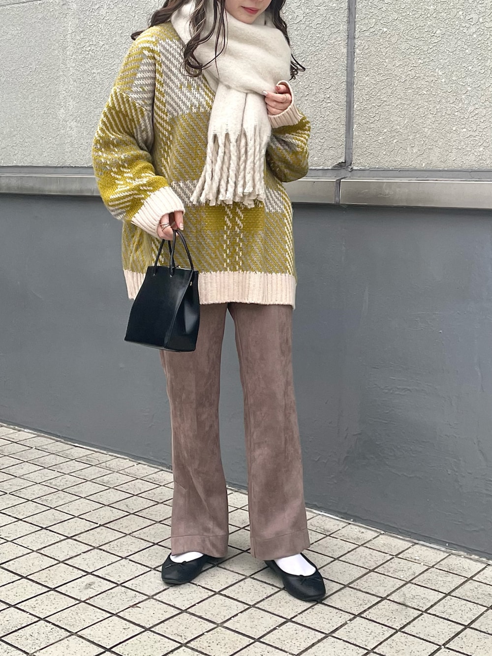 ホワイト系のニット/セーター、ブラック系のショルダーバッグ、ブラウン系のスラックスを着用したレディースの冬コーディネートの2枚目の写真