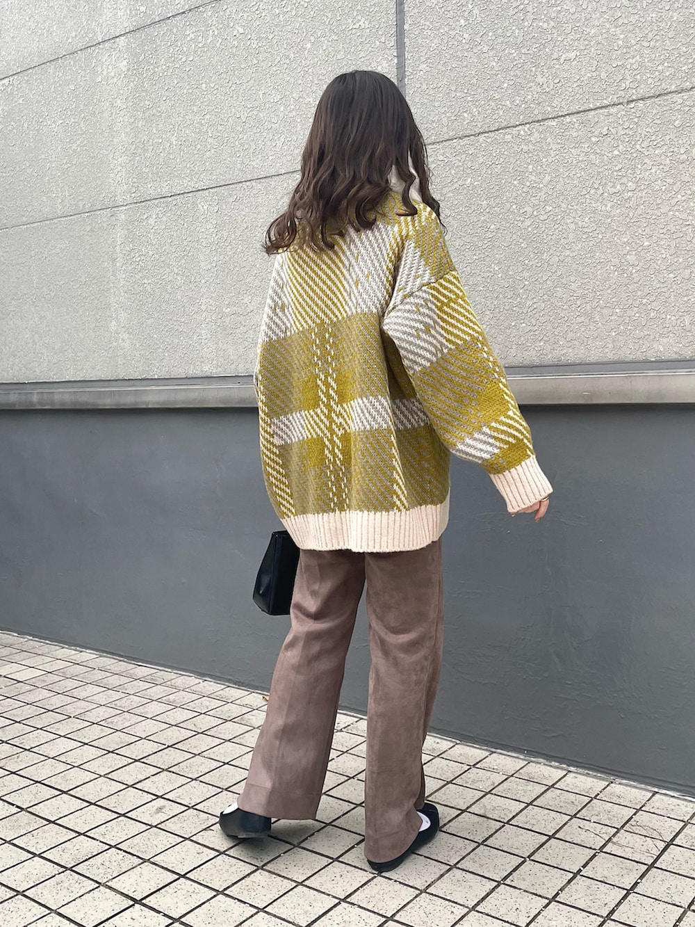 ホワイト系のニット/セーター、ブラック系のショルダーバッグ、ブラウン系のスラックスを着用したレディースの冬コーディネートの3枚目の写真