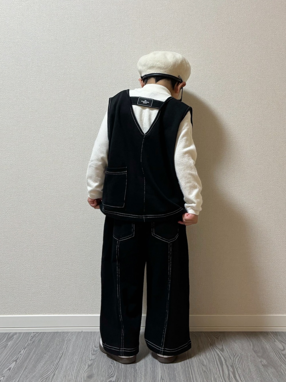 ブラック系のトップス、ブラック系のパンツ、ホワイト系のスニーカーを着用したキッズの秋コーディネートの2枚目の写真
