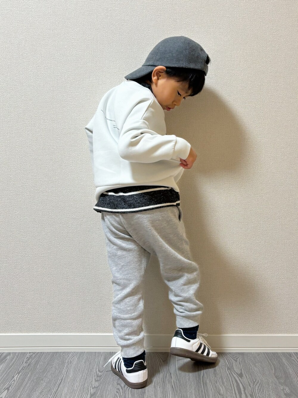 グレー系のパンツ、グレー系のトップス、ホワイト系のスウェットを着用したキッズの秋コーディネートの3枚目の写真