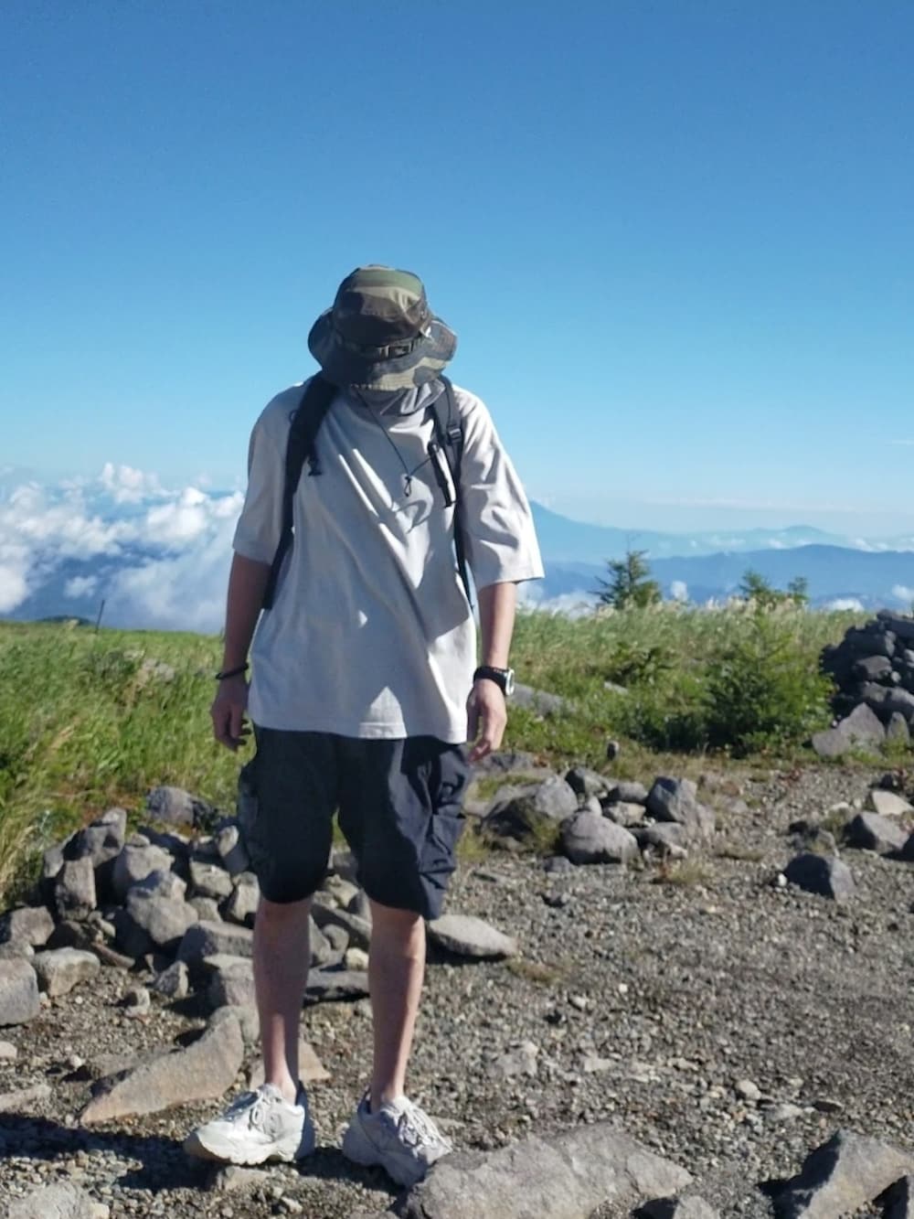 シルバー系のスニーカー、ブラック系のカーゴパンツ、ブラック系のバックパック/リュックを着用したメンズの夏コーディネートの2枚目の写真