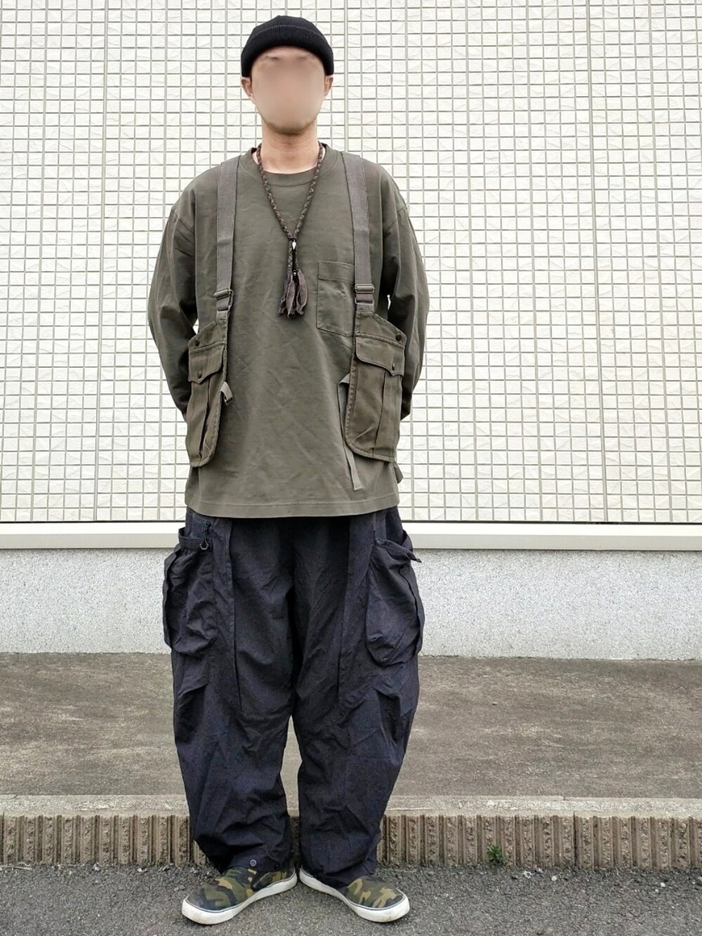 ブラック系のカーゴパンツ、グリーン系のスリッポン、グリーン系のベストを着用したメンズの春コーディネートの2枚目の写真