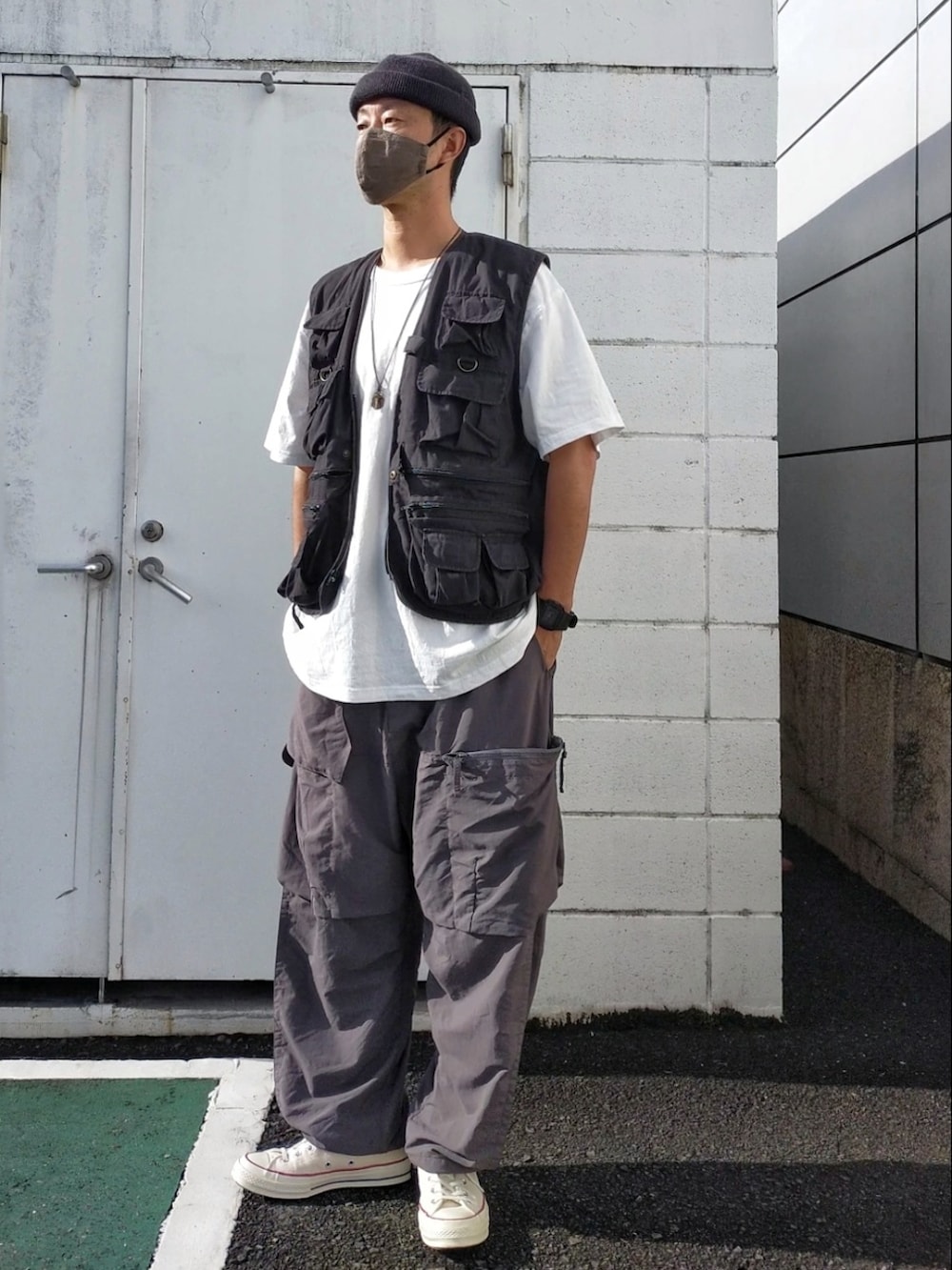 ホワイト系のスニーカー、ブラック系のベスト、グレー系のカーゴパンツを着用したメンズの秋コーディネートの2枚目の写真