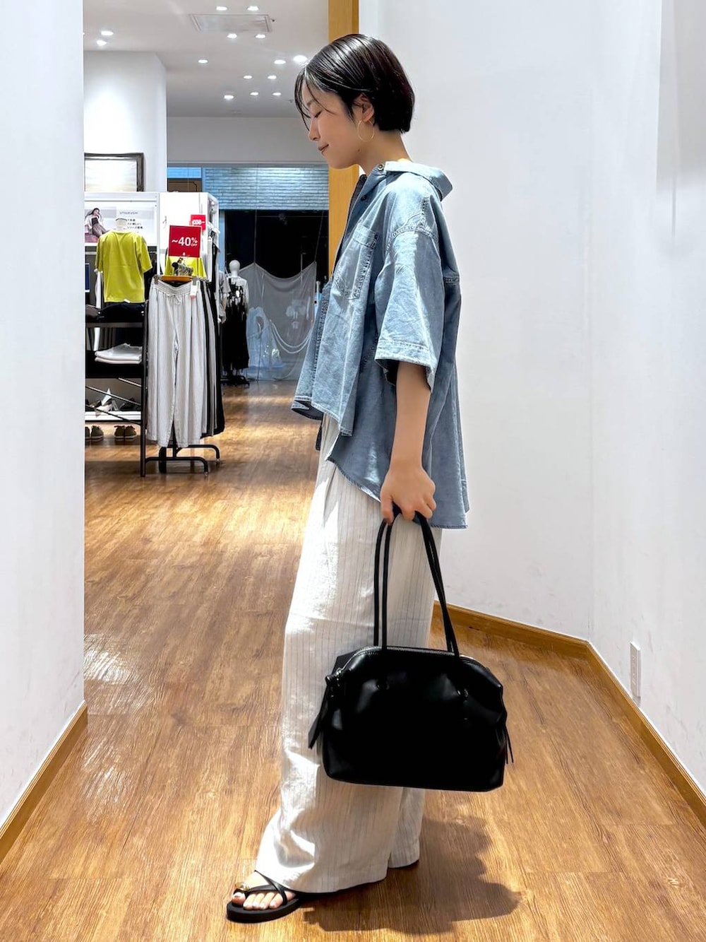 ブラック系のボストンバッグ、ベージュ系のその他パンツ、ブルー系のシャツ/ブラウスを着用したレディースの夏コーディネートの2枚目の写真