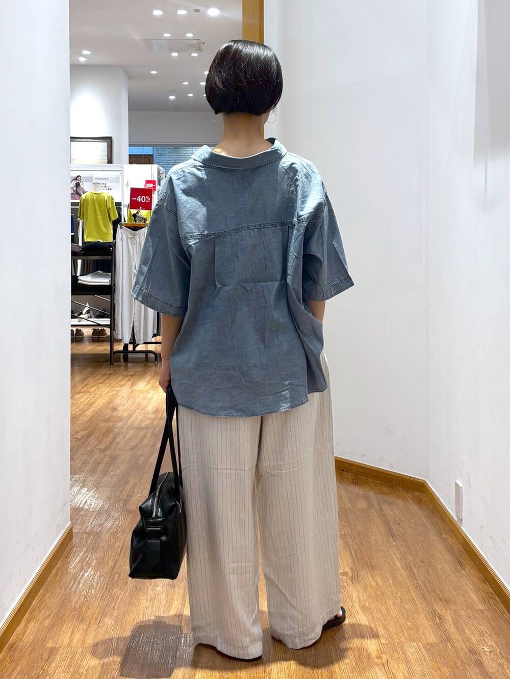 ブラック系のボストンバッグ、ベージュ系のその他パンツ、ブルー系のシャツ/ブラウスを着用したレディースの夏コーディネートの3枚目の写真