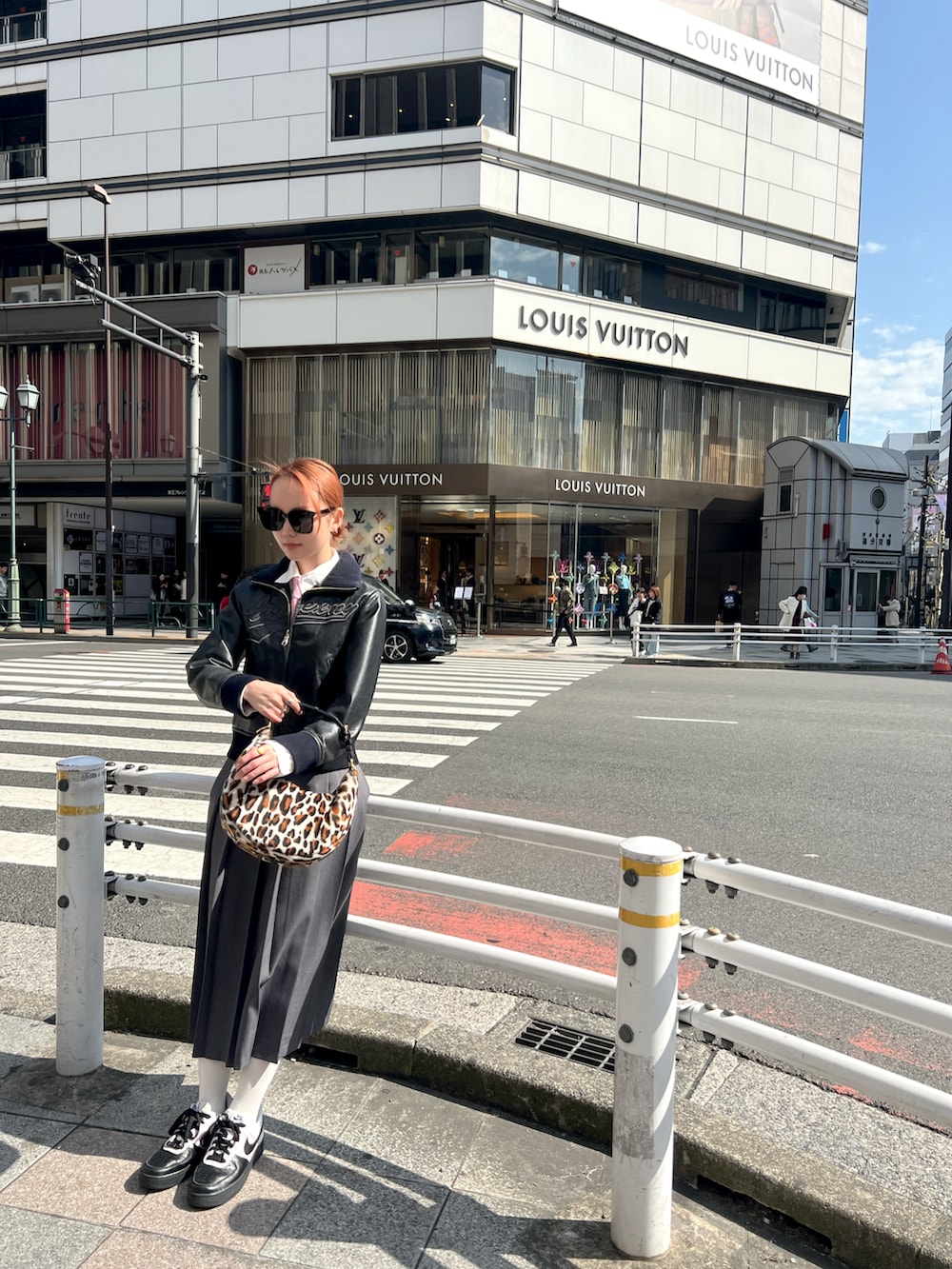 グレー系のスカート、ブラック系のスニーカー、ブラック系のサングラスを着用したレディースの冬コーディネートの2枚目の写真