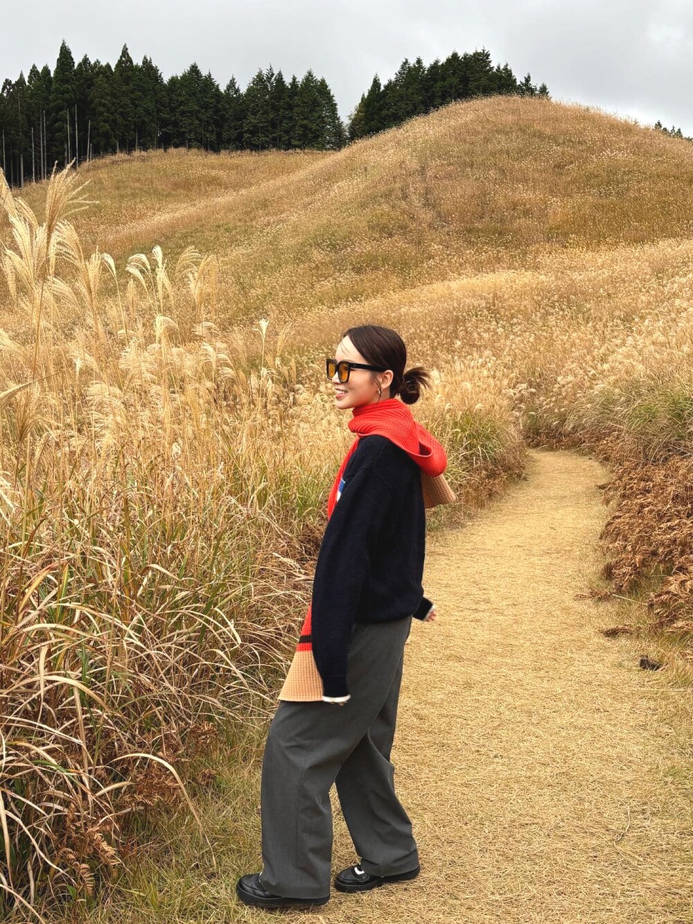 グレー系のスラックス、ブルー系のニット/セーターを着用したレディースの冬コーディネートの2枚目の写真