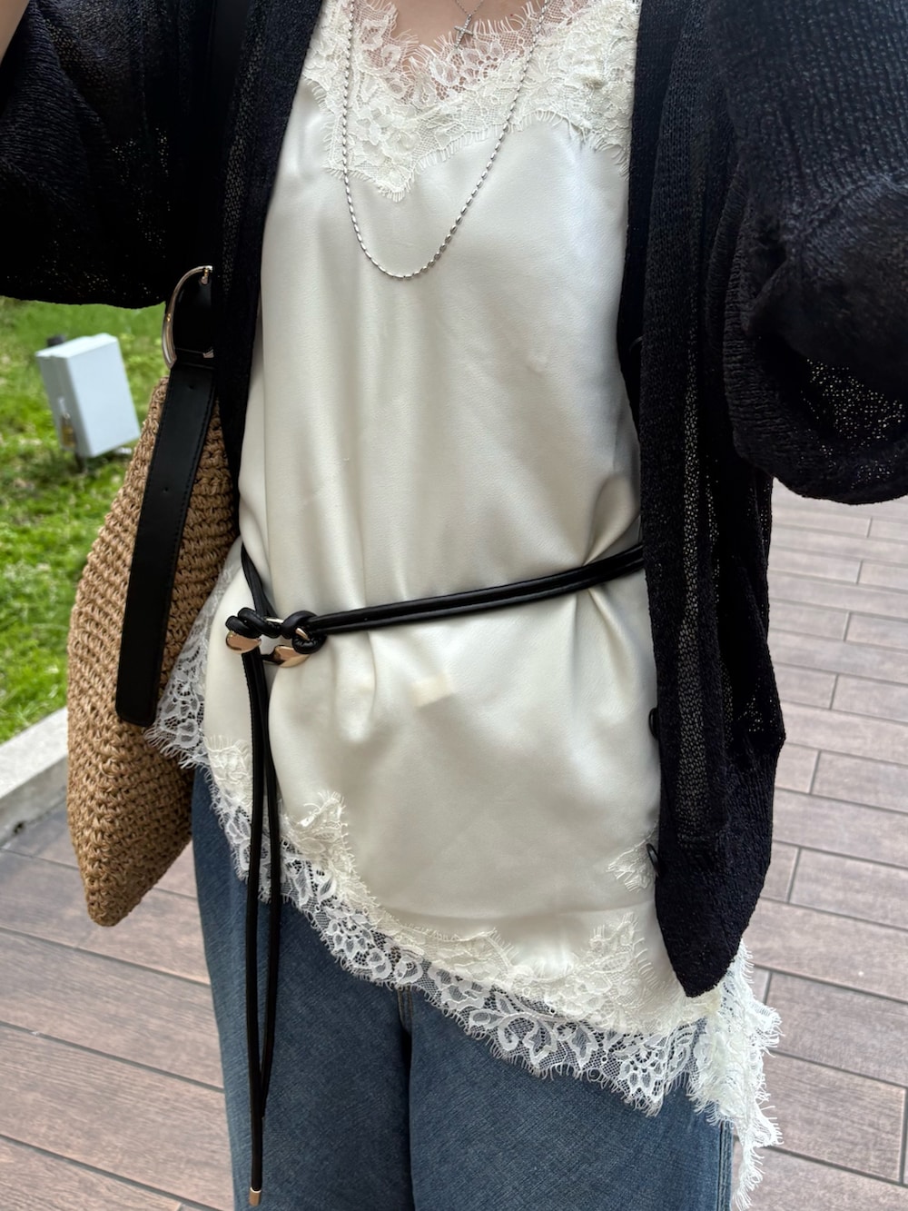 ブラック系のカーディガン/ボレロ、ホワイト系のシャツ/ブラウス、ブルー系のデニムパンツを着用したレディースの春コーディネートの4枚目の写真