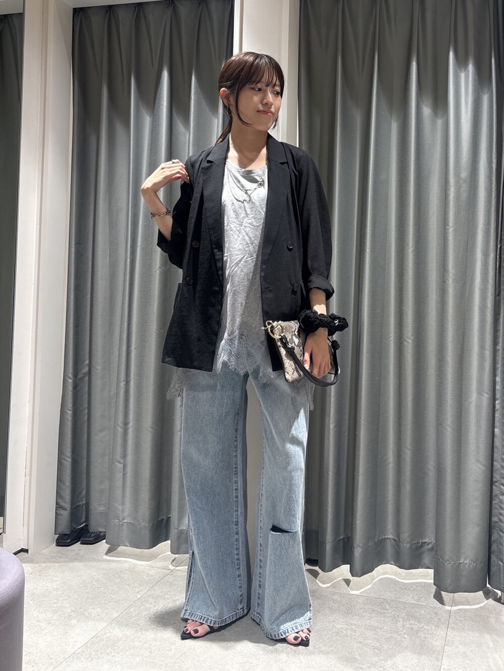 ブラック系のテーラードジャケット、グレー系のTシャツ/カットソー、ブルー系のデニムパンツを着用したレディースの春コーディネートの6枚目の写真