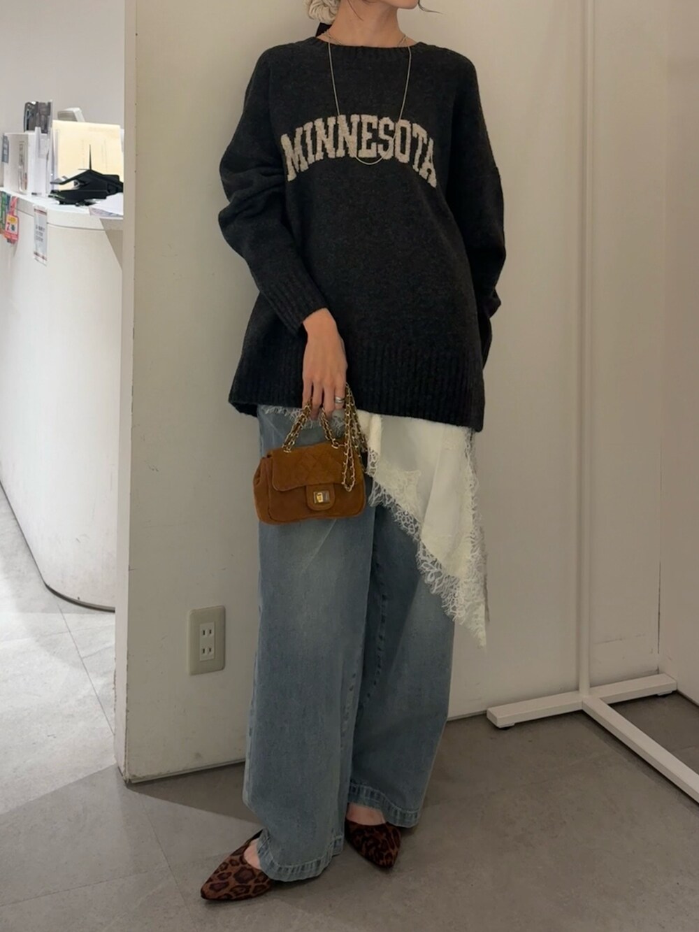 グレー系のニット/セーター、ホワイト系のキャミソール、ブルー系のデニムパンツを着用したレディースの冬コーディネートの3枚目の写真