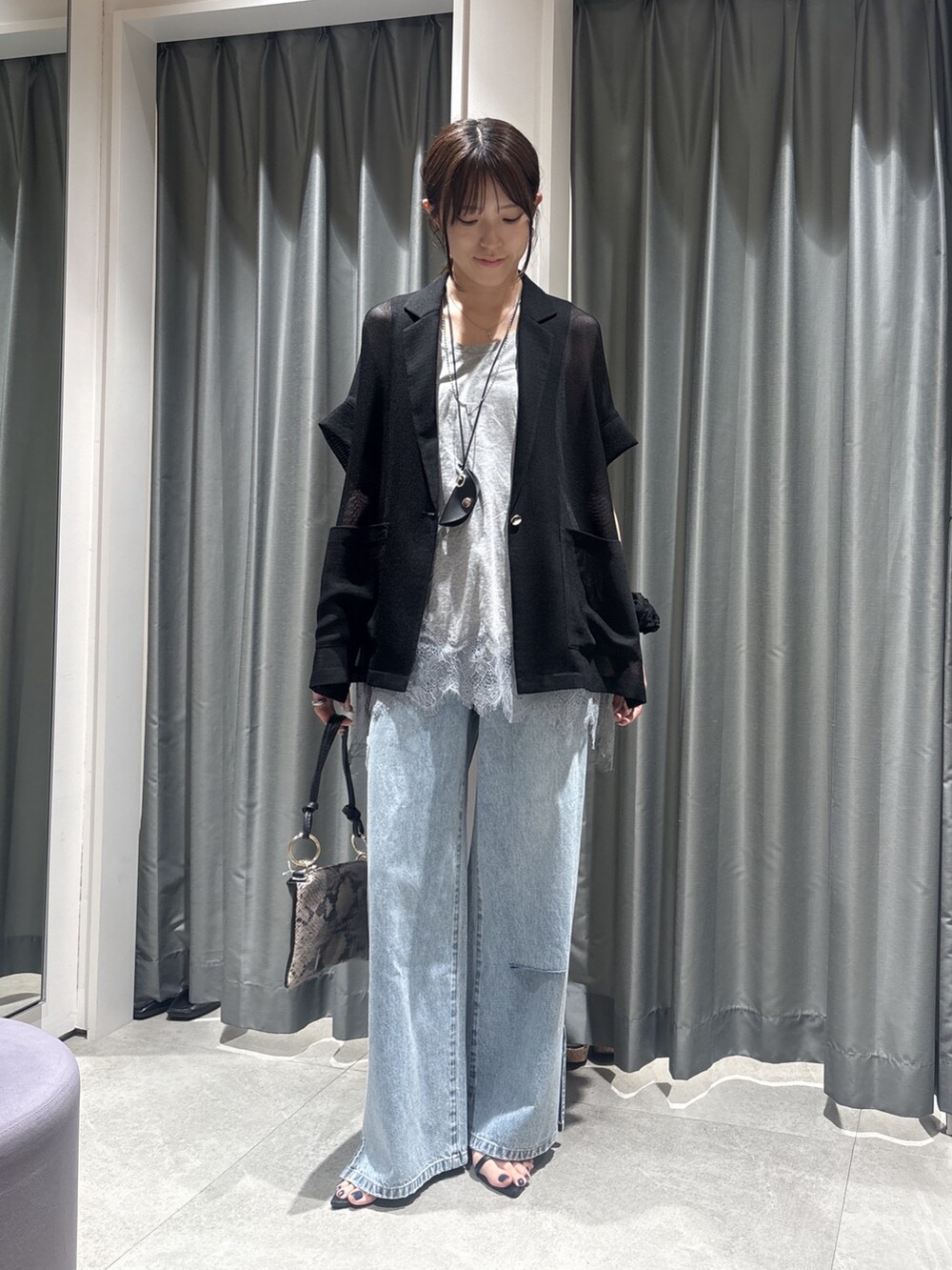 ブラック系のテーラードジャケット、グレー系のTシャツ/カットソー、ブルー系のデニムパンツを着用したレディースの春コーディネートの4枚目の写真
