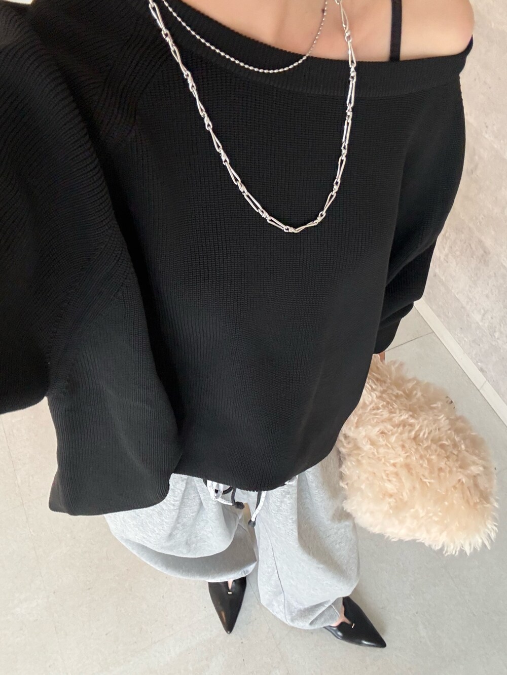 ブラック系のニット/セーター、ホワイト系のショルダーバッグ、ブラック系のパンプスを着用したレディースの秋コーディネートの3枚目の写真