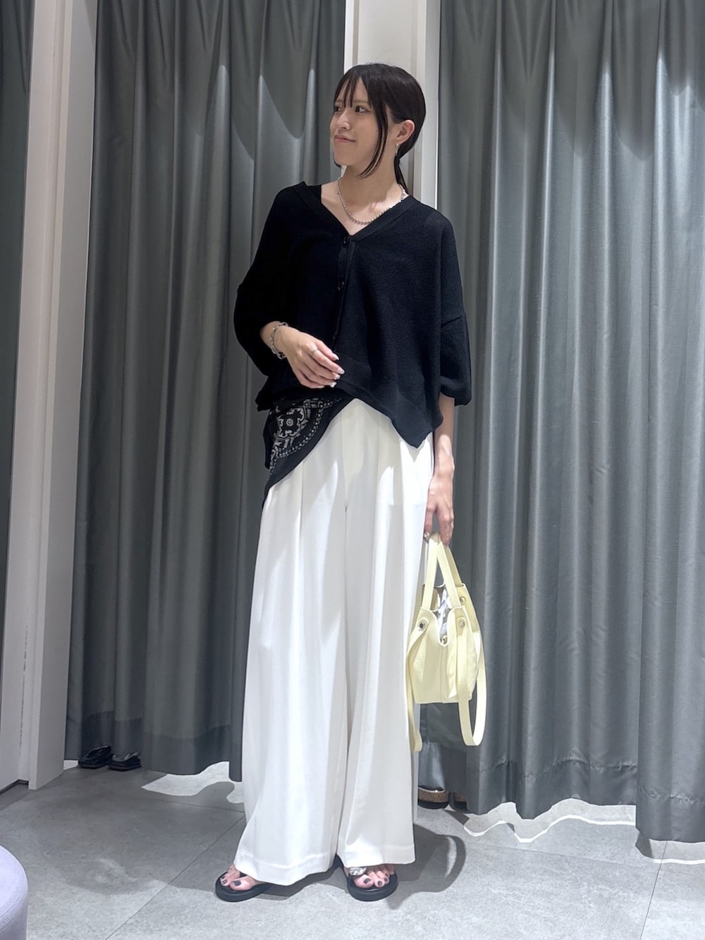 ホワイト系のスラックス、ブラック系のカーディガン/ボレロ、ブラック系のストール/ショールを着用したレディースの夏コーディネートの2枚目の写真
