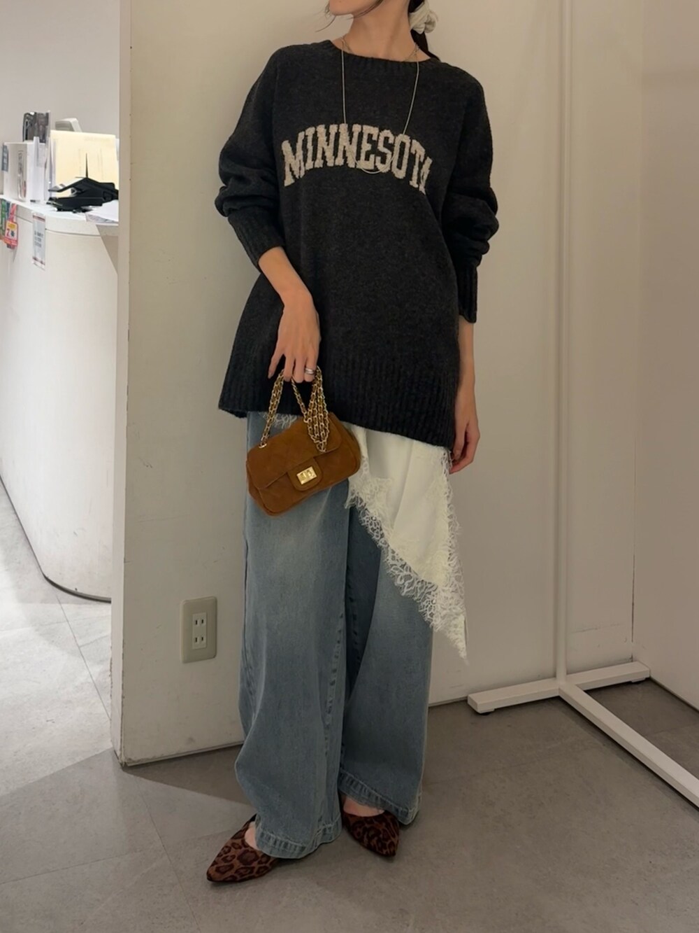 グレー系のニット/セーター、ホワイト系のキャミソール、ブルー系のデニムパンツを着用したレディースの冬コーディネートの2枚目の写真