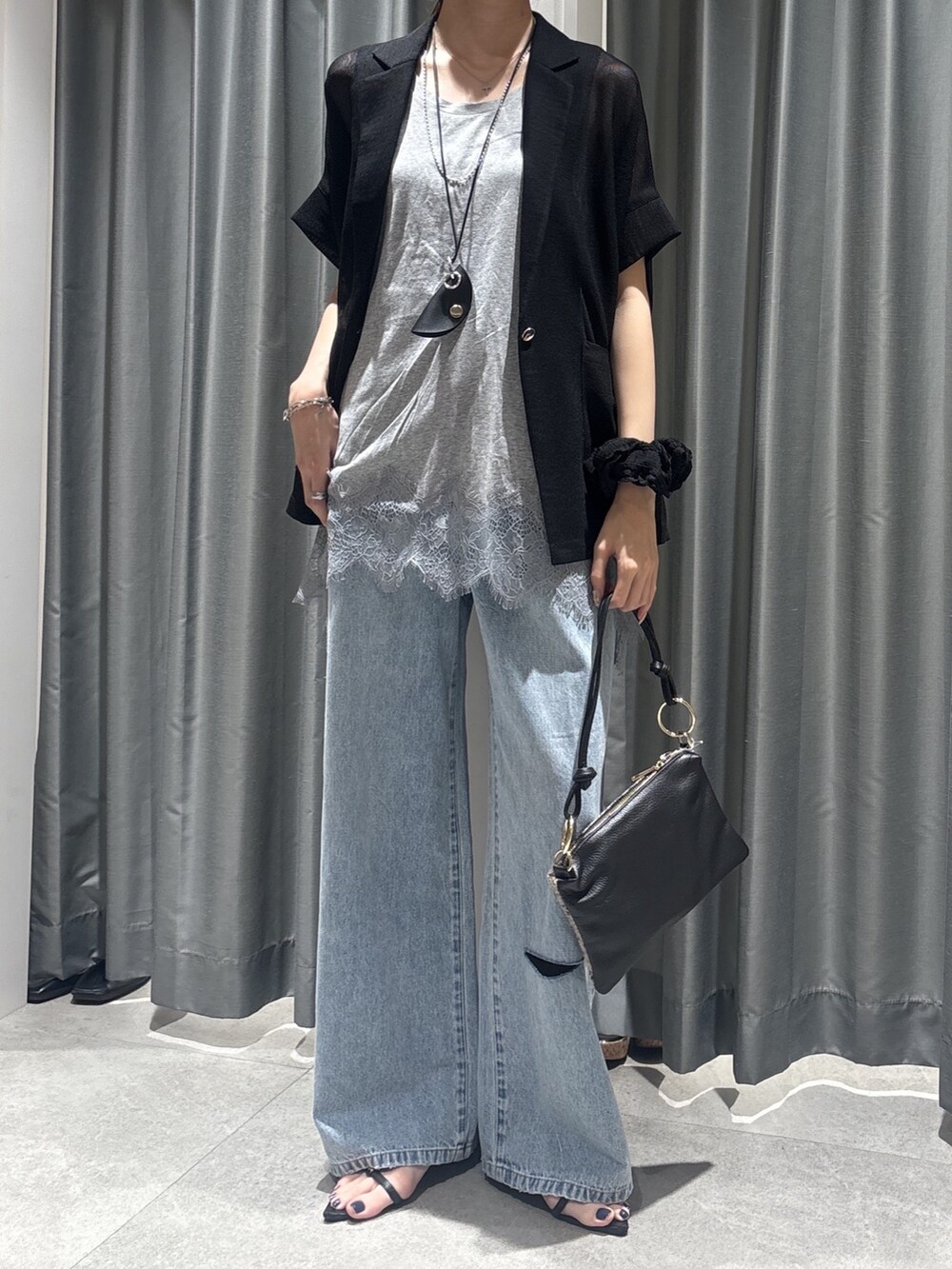 ブラック系のテーラードジャケット、グレー系のTシャツ/カットソー、ブルー系のデニムパンツを着用したレディースの春コーディネートの2枚目の写真