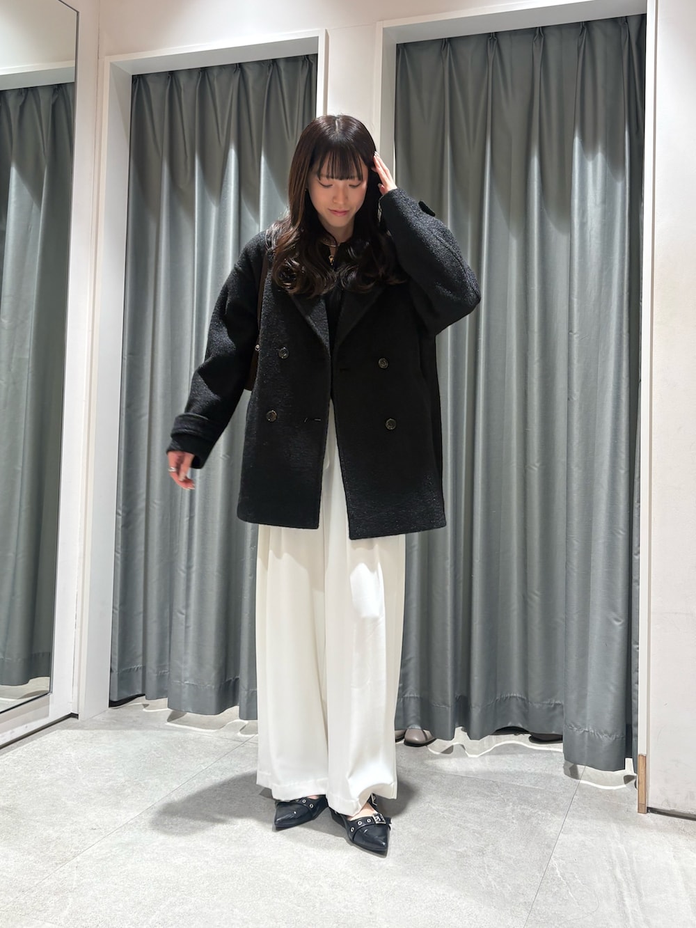 ブラック系のその他アウター、ブラック系のニット/セーター、ホワイト系のスラックスを着用したレディースの秋コーディネートの2枚目の写真