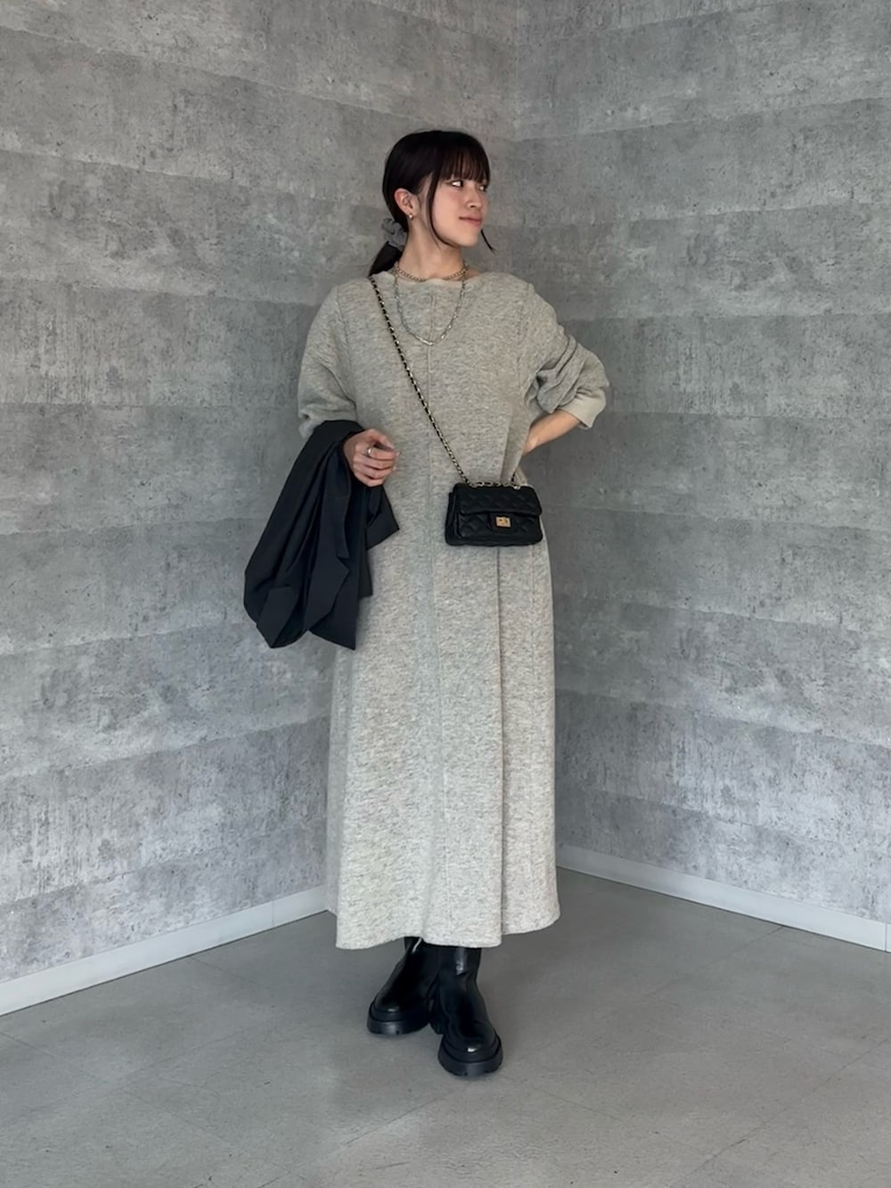 グレー系のテーラードジャケット、ブラック系のショルダーバッグ、ブラック系のブーツを着用したレディースの秋コーディネートの2枚目の写真