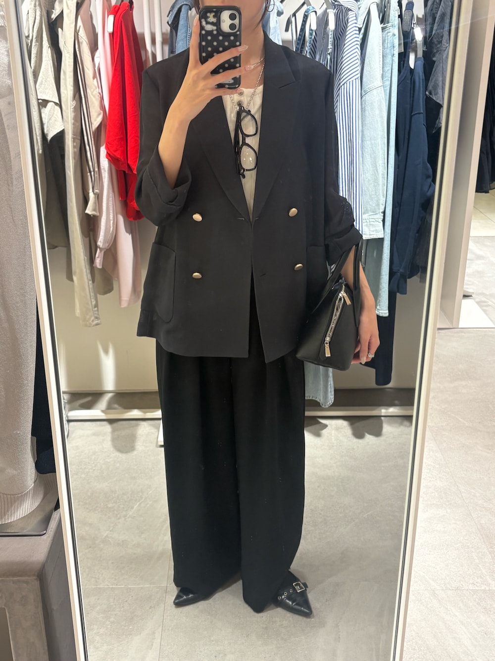 グレー系のテーラードジャケット、ホワイト系のニット/セーター、ブラック系のスラックスを着用したレディースの春コーディネートの2枚目の写真