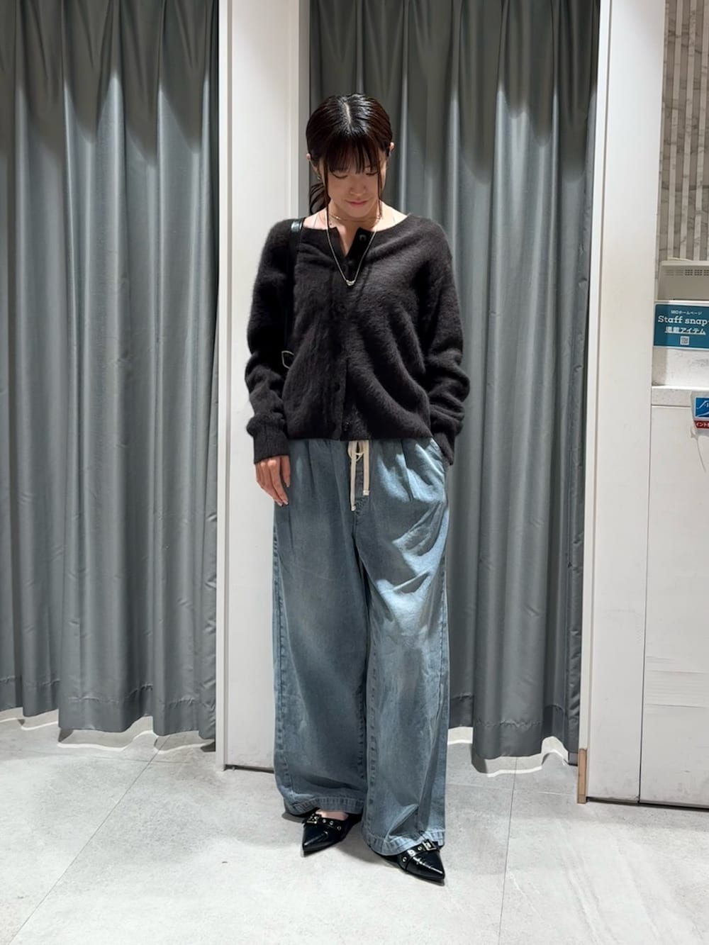 ブラック系のショルダーバッグ、ブルー系のデニムパンツ、ブラウン系のカーディガン/ボレロを着用したレディースの秋コーディネートの3枚目の写真