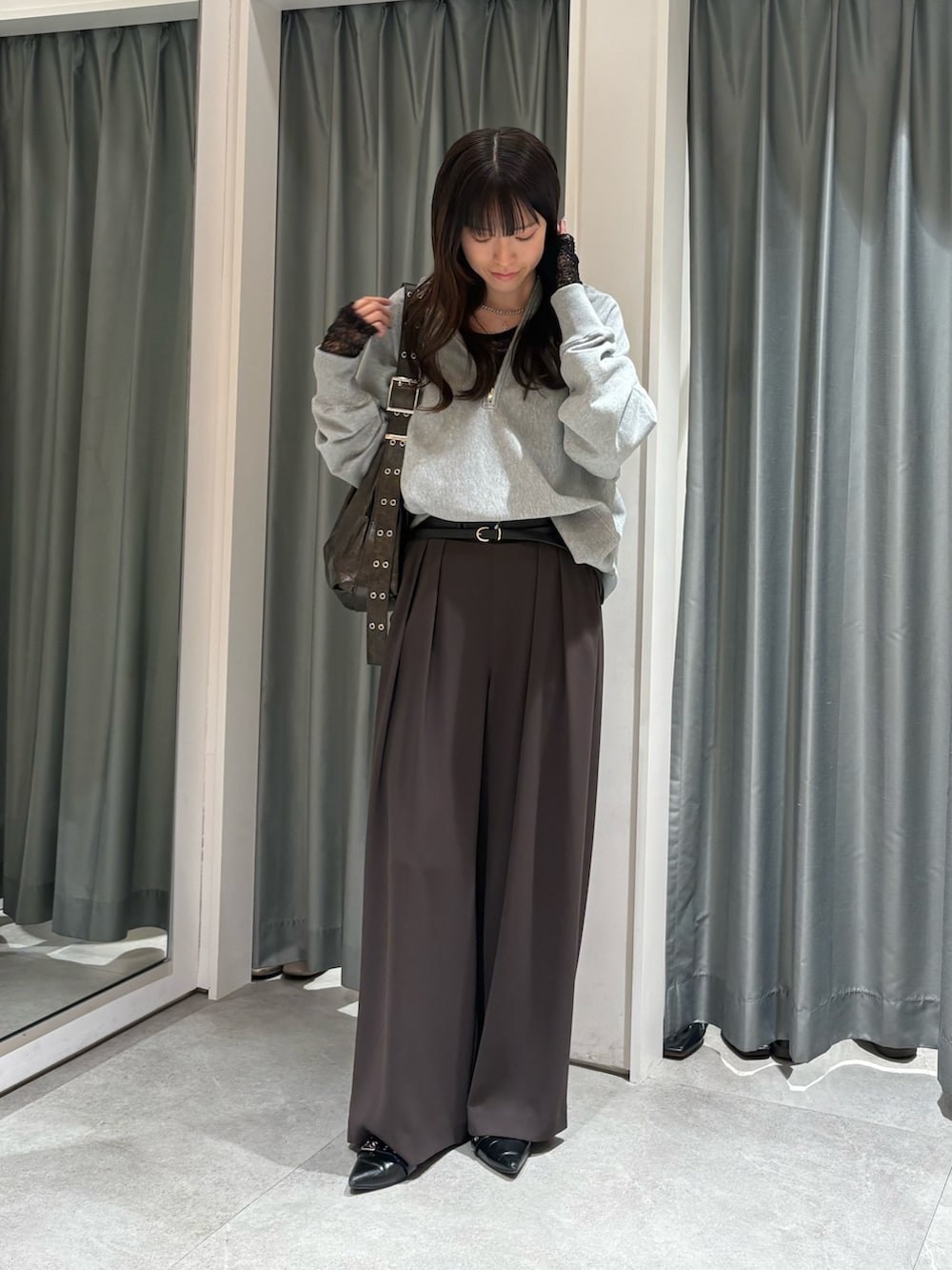 グレー系のスウェット、ブラック系のTシャツ/カットソー、ブラウン系のスラックスを着用したレディースの冬コーディネートの2枚目の写真