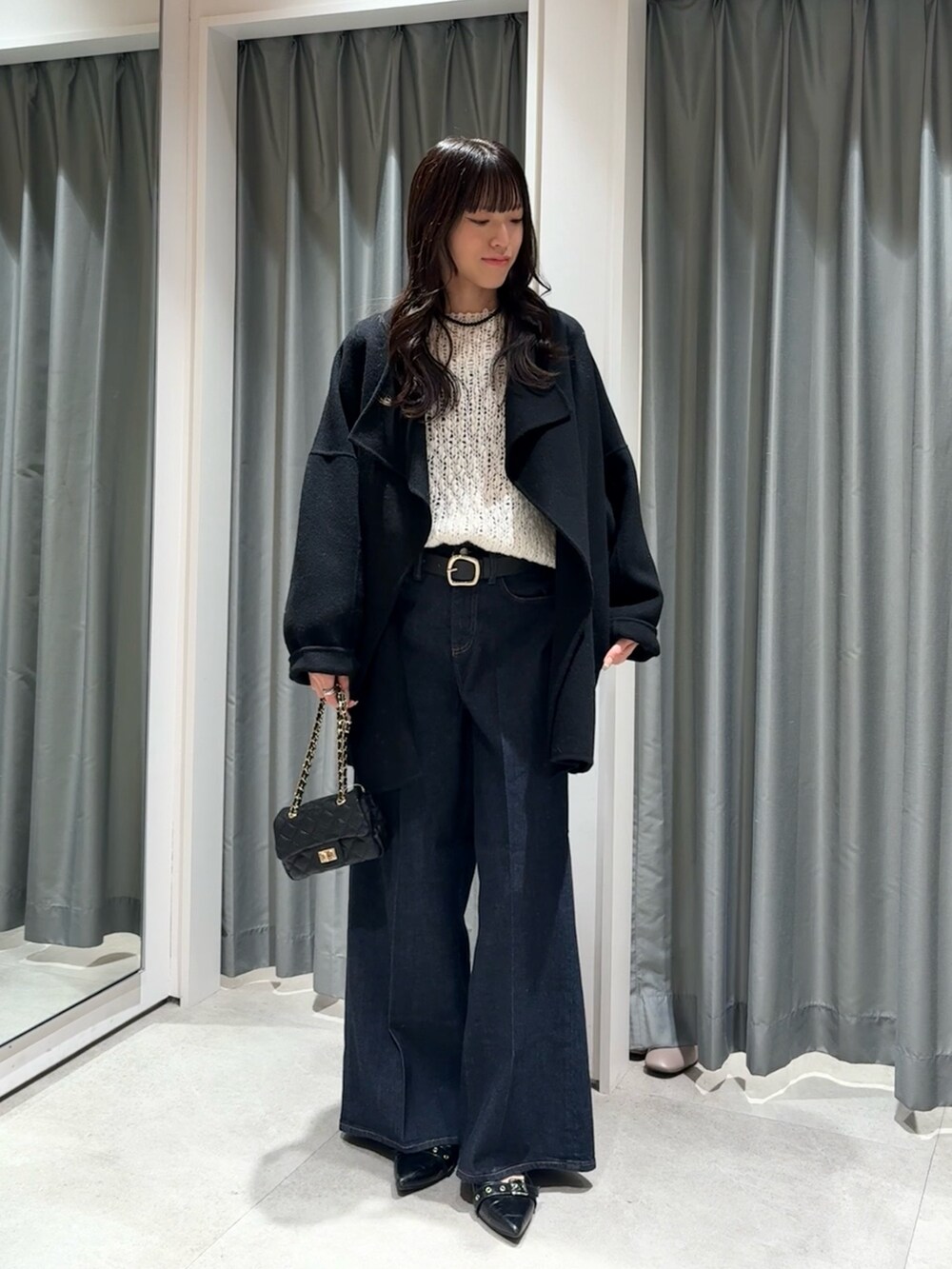 ブラック系のその他アウター、ホワイト系のニット/セーター、ブラック系のベルトを着用したレディースの秋コーディネートの2枚目の写真