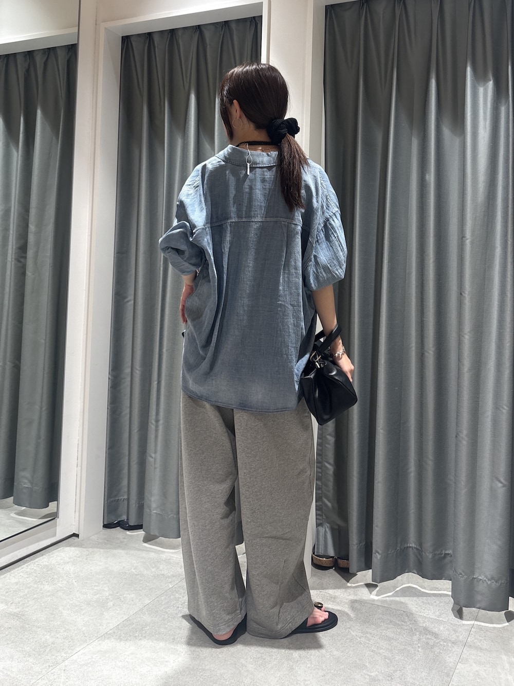 ブルー系のシャツ/ブラウス、ブラック系のニット/セーター、グレー系のその他パンツを着用したレディースの春コーディネートの2枚目の写真