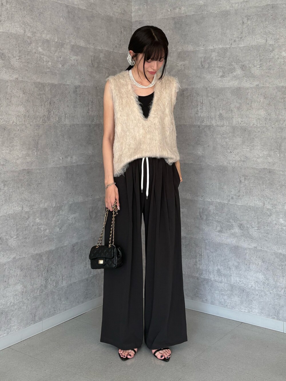 ベージュ系のニット/セーター、グレー系のその他パンツ、ブラック系のショルダーバッグを着用したレディースの夏コーディネートの2枚目の写真