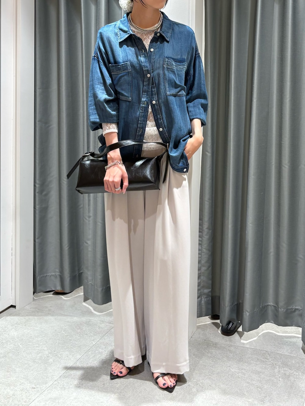 ブラック系のショルダーバッグ、ブルー系のシャツ/ブラウス、グレー系のスラックスを着用したレディースの夏コーディネートの2枚目の写真