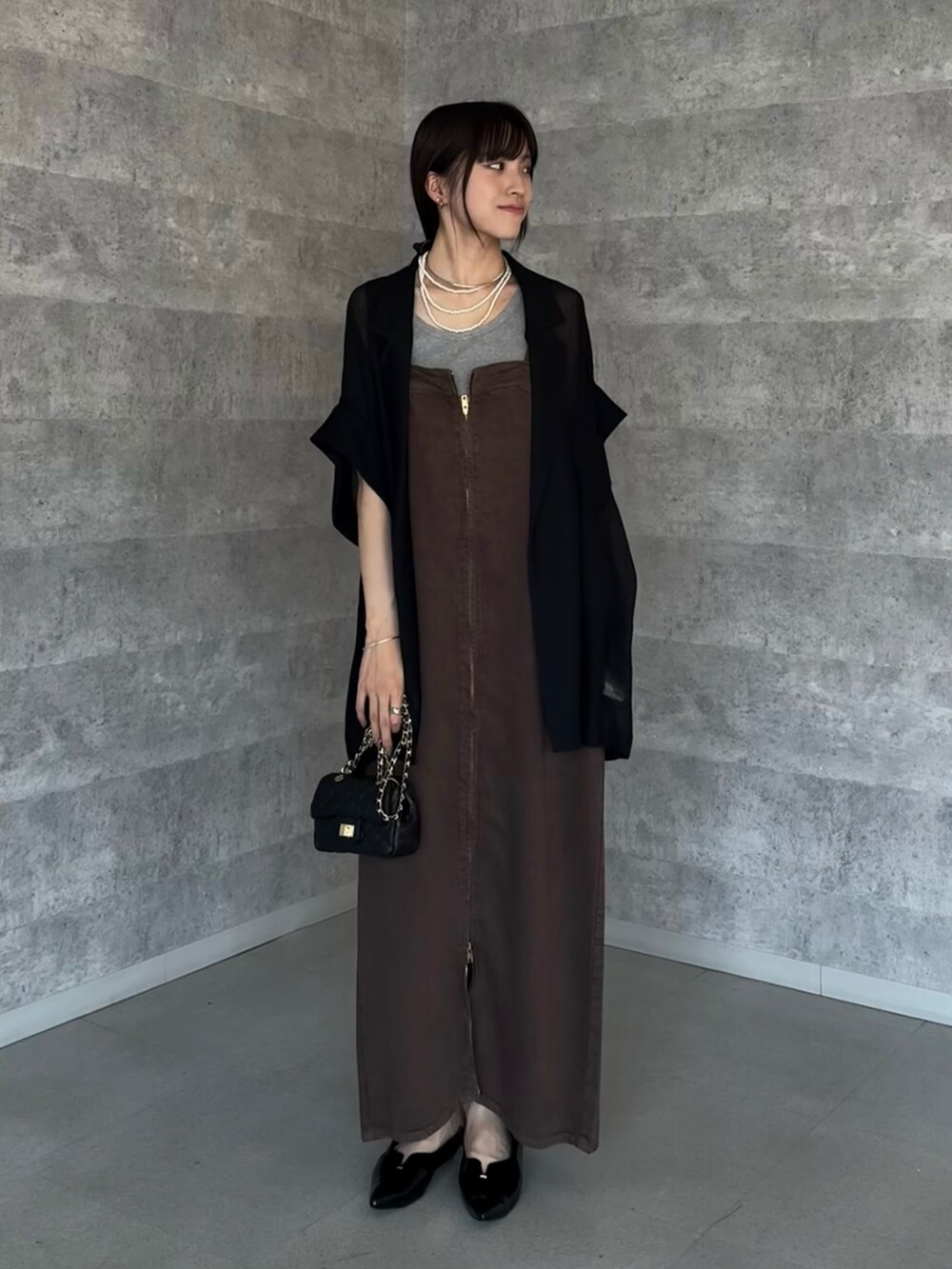 ブラック系のテーラードジャケット、ブラウン系のワンピース、ブラック系のショルダーバッグを着用したレディースの夏コーディネートの2枚目の写真