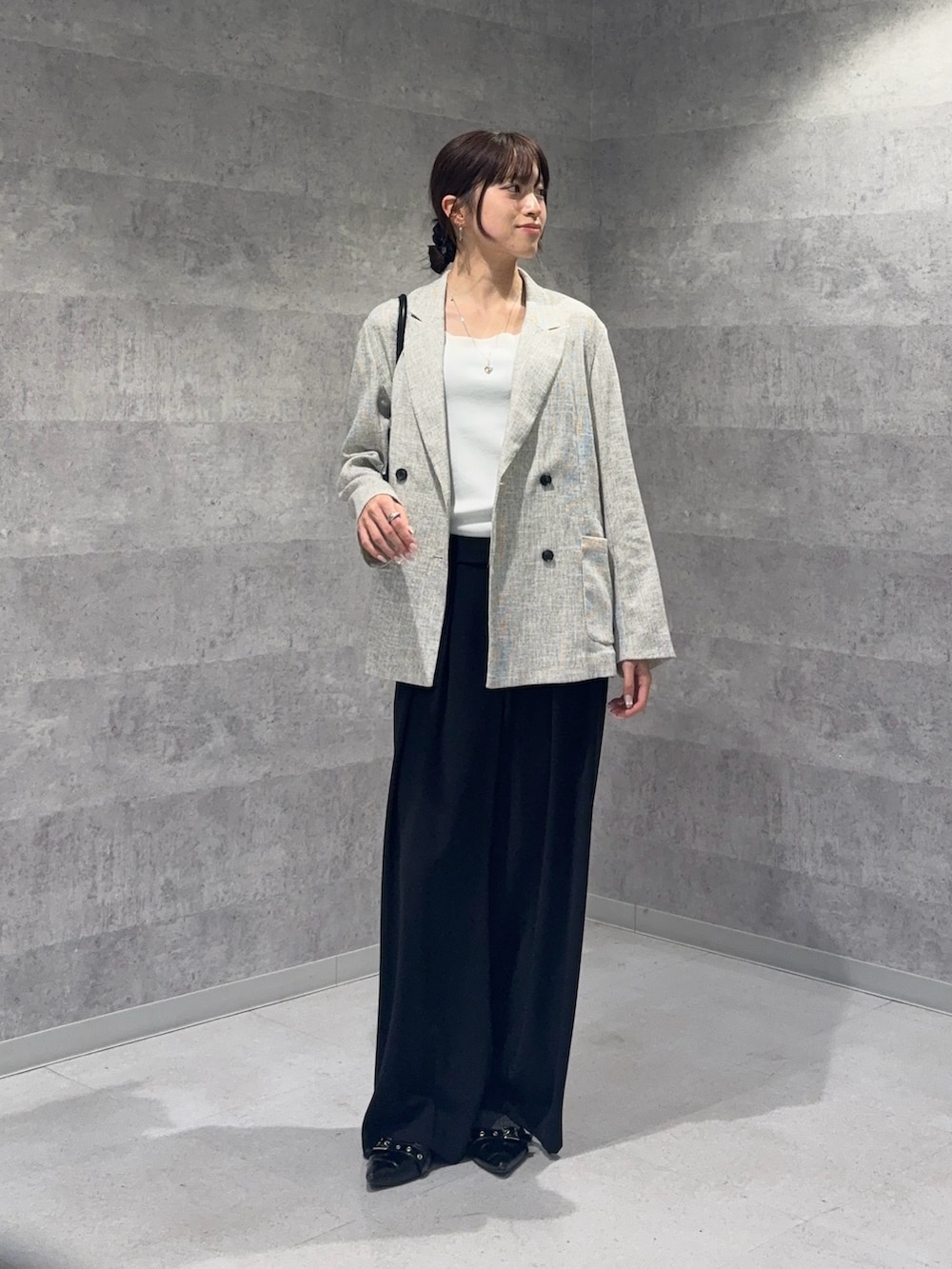 ホワイト系のテーラードジャケット、ホワイト系のニット/セーター、ブラック系のスラックスを着用したレディースの春コーディネートの2枚目の写真