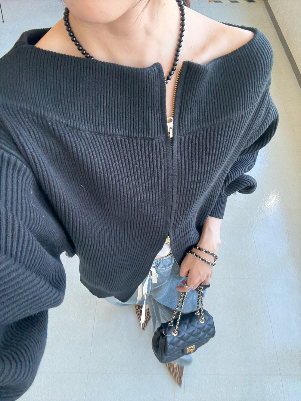 ブラック系のニット/セーター、ブラック系のショルダーバッグ、ブルー系のその他パンツを着用したレディースの秋コーディネートの4枚目の写真