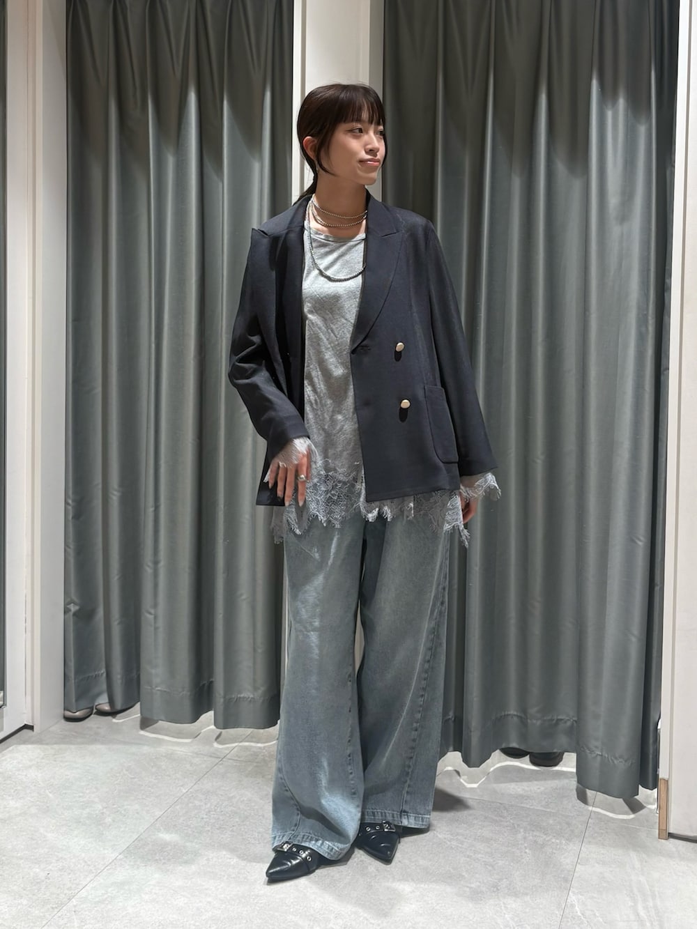 グレー系のテーラードジャケット、グレー系のTシャツ/カットソー、ブルー系のデニムパンツを着用したレディースの冬コーディネートの2枚目の写真