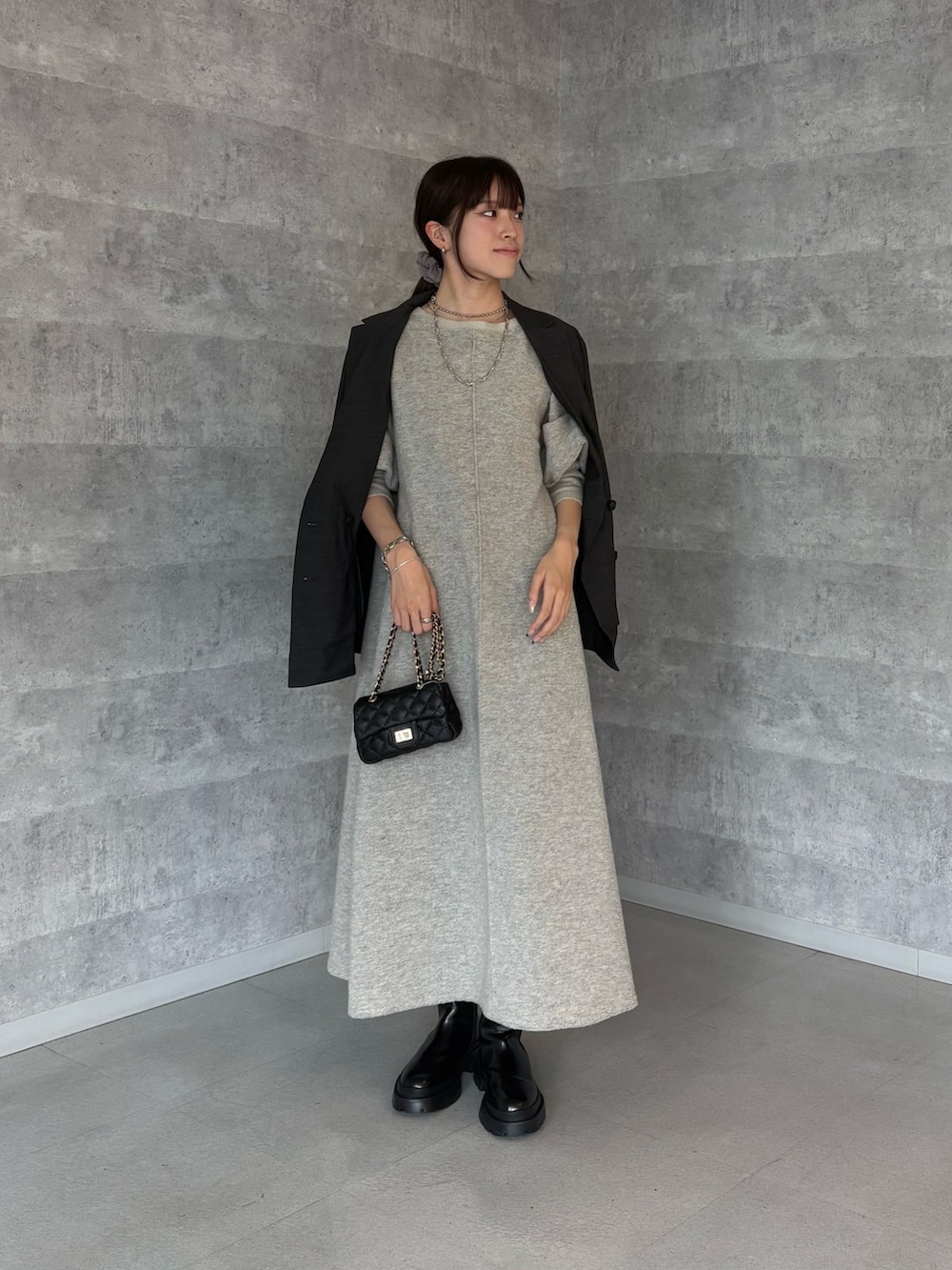 グレー系のテーラードジャケット、ブラック系のショルダーバッグ、ブラック系のブーツを着用したレディースの秋コーディネートの3枚目の写真