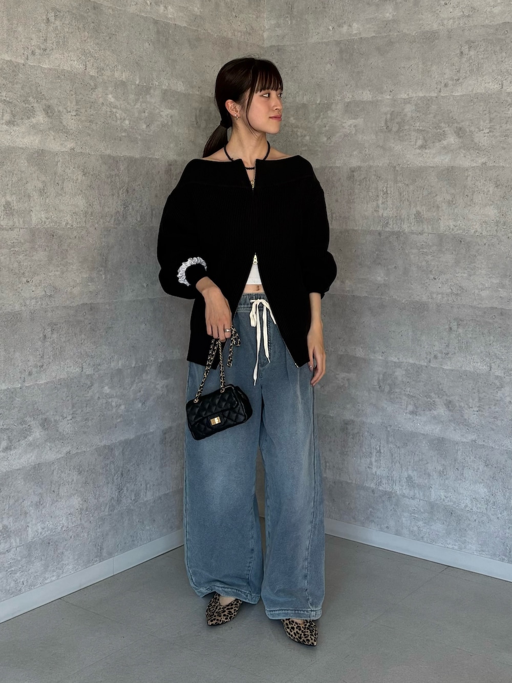 ブラック系のニット/セーター、ブラック系のショルダーバッグ、ブルー系のその他パンツを着用したレディースの秋コーディネートの2枚目の写真