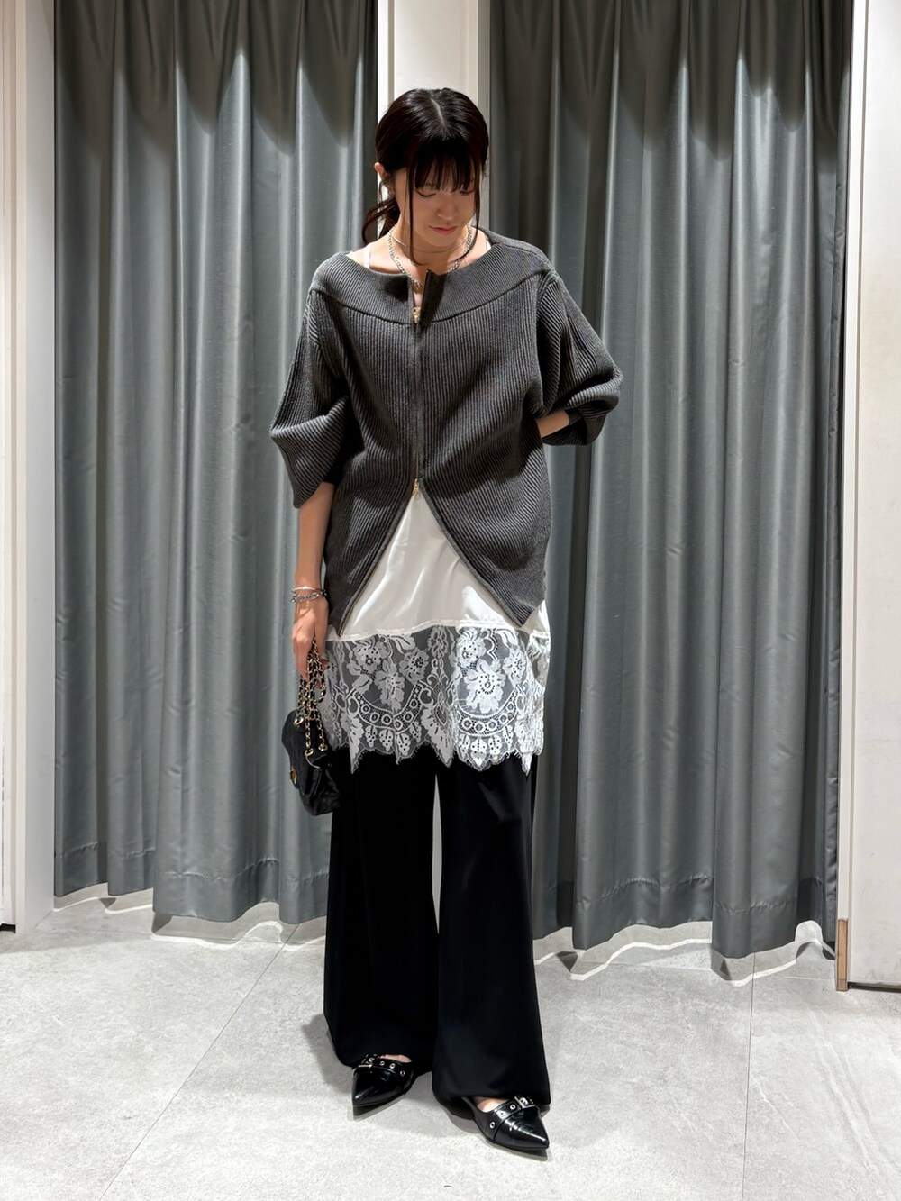 グレー系のニット/セーター、ホワイト系のシャツ/ブラウス、ブラック系のその他パンツを着用したレディースの秋コーディネートの2枚目の写真